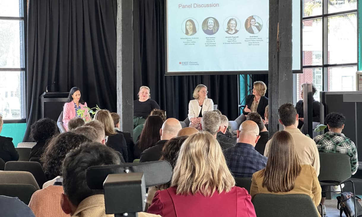 A panel of speakers talking in front of a seated audience