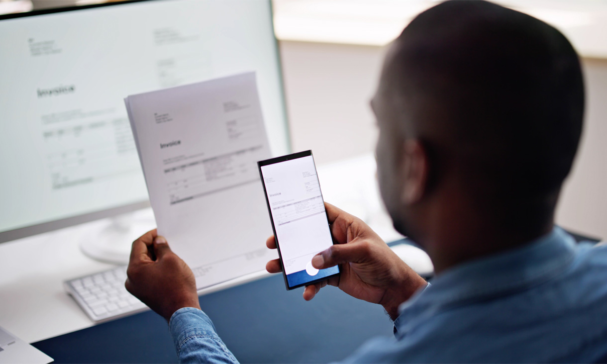 A person taking a photo of their forms using a smartphone.