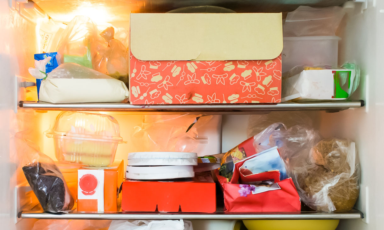 A full fridge stacked with takeaway boxes and bags of half eaten food.