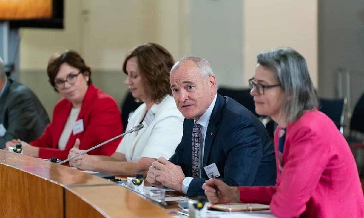 Professor Alec Cameron speaking while sitting at a round table