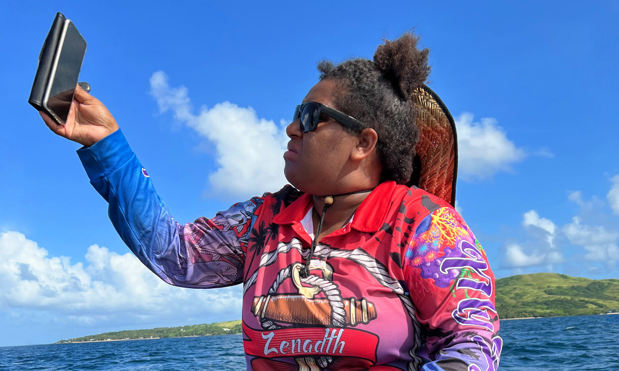 Co-researcher Lala Gutchen raising her phone for internet reception while taking the team out fishing.