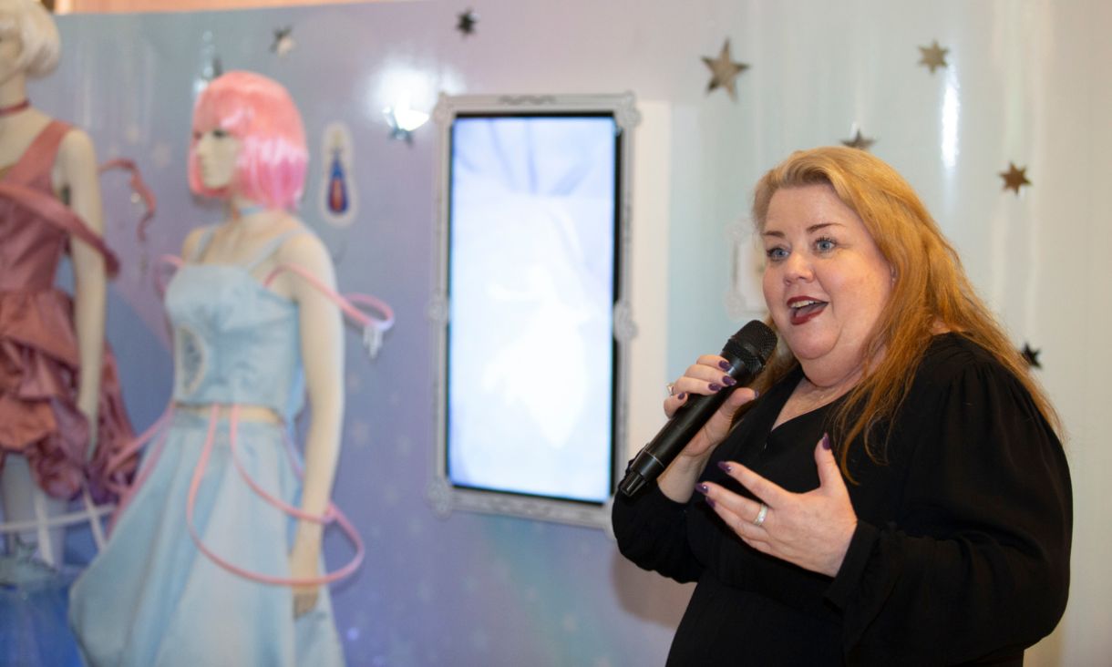 Mish Eastman speaking in front of mannequins featuring student designs