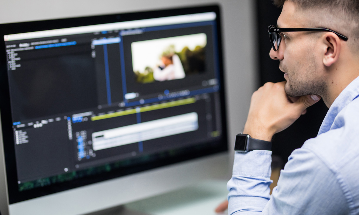 A journalist is looking at footage that is being edited on a computer.