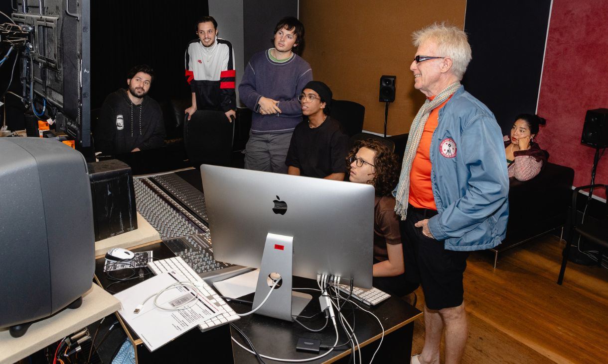 Students and Dave Anderson gathered around controls looking into recording booth
