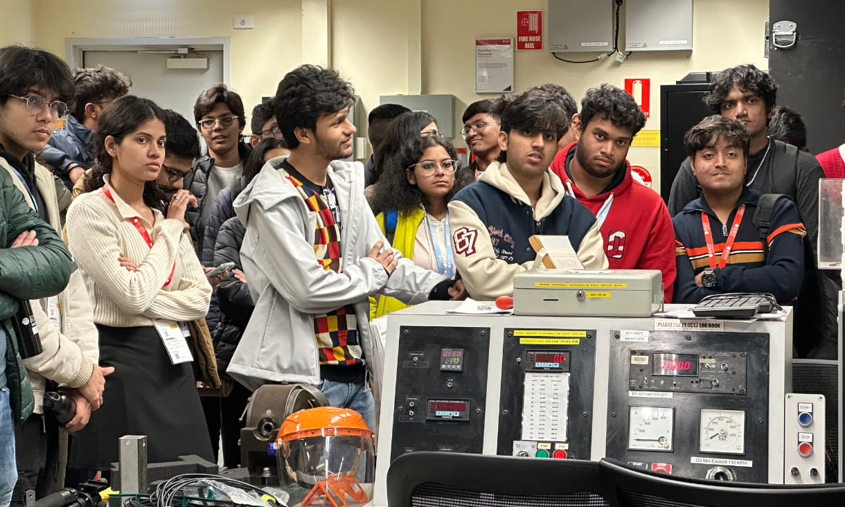 A crowd of students standing around machines in a laboratory.
