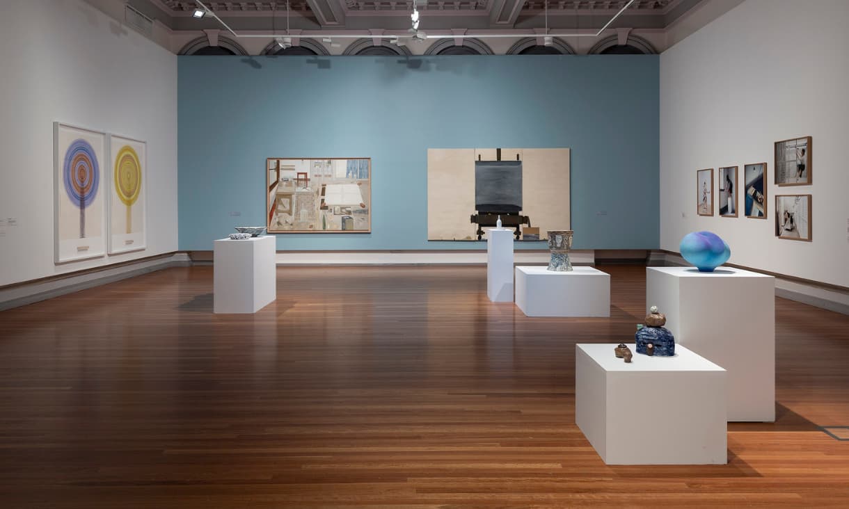 A wide shot of a room with paintings, prints and sculptures 