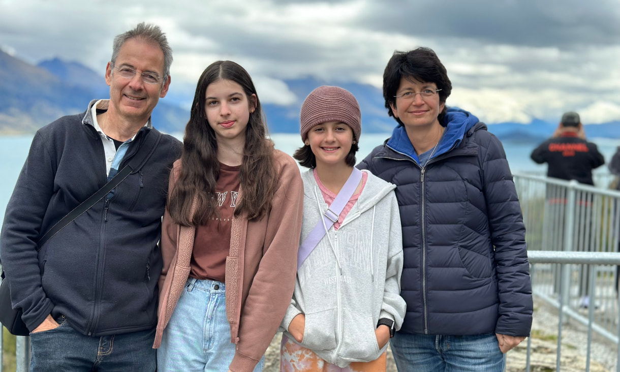 A family with a man, a woman and two daughters in front of a large lake