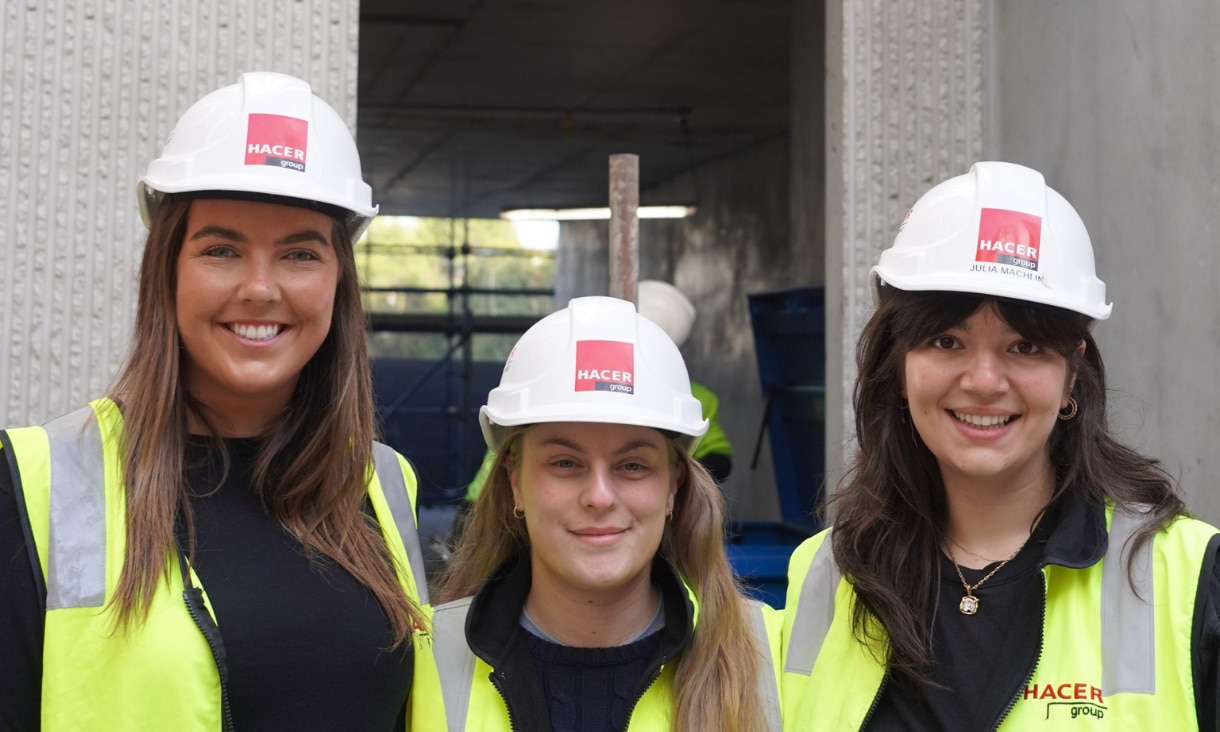 Three young women in yellow high-vis vests and hard hats.
