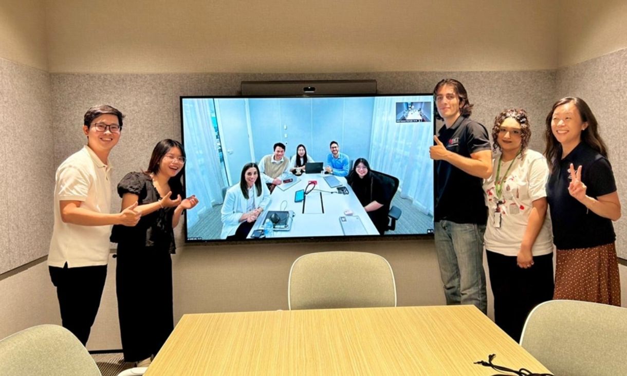 A group of five people in Vietnam office video calling a group of people in the Melbourne office.