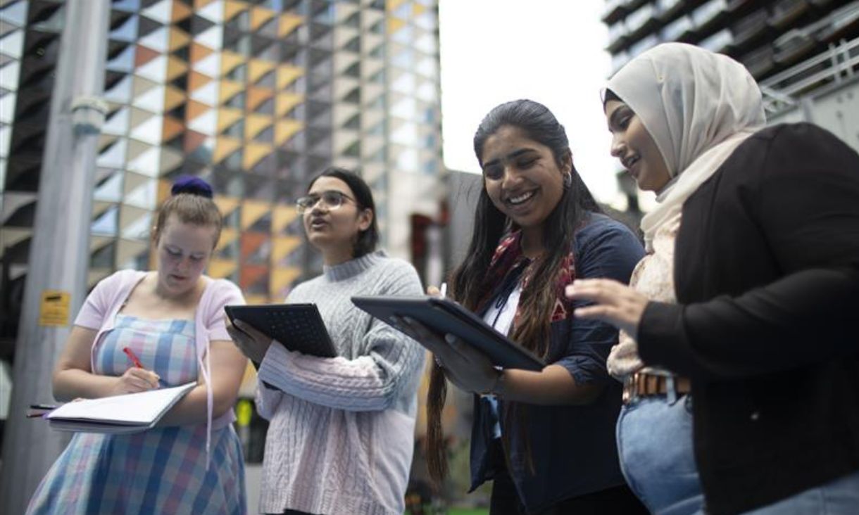 Group of students holding tablets with RMIT building in background