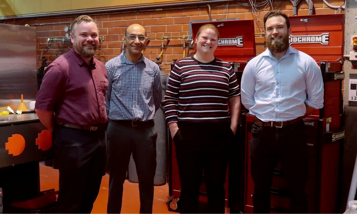 Four researchers stand in front of red tool cabinets in a workshop space at RMIT's Centre for Additive Manufacturing.