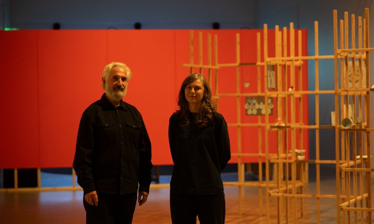 (L-R) Professor Philip Samartzis stands and RMIT Media & Communications Senior Lecturer, Dr Polly Stanton in a red room. Credit: Keelan O'Hehir 
