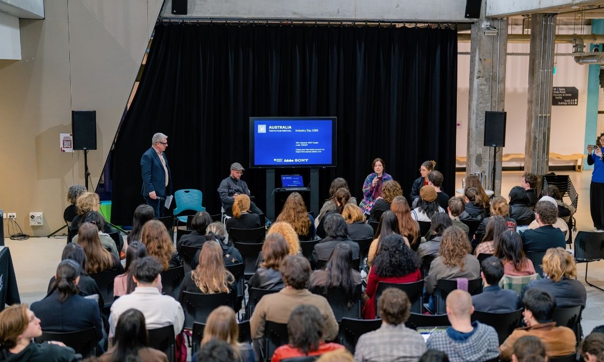 A large group of people sit and watch a panel discussion