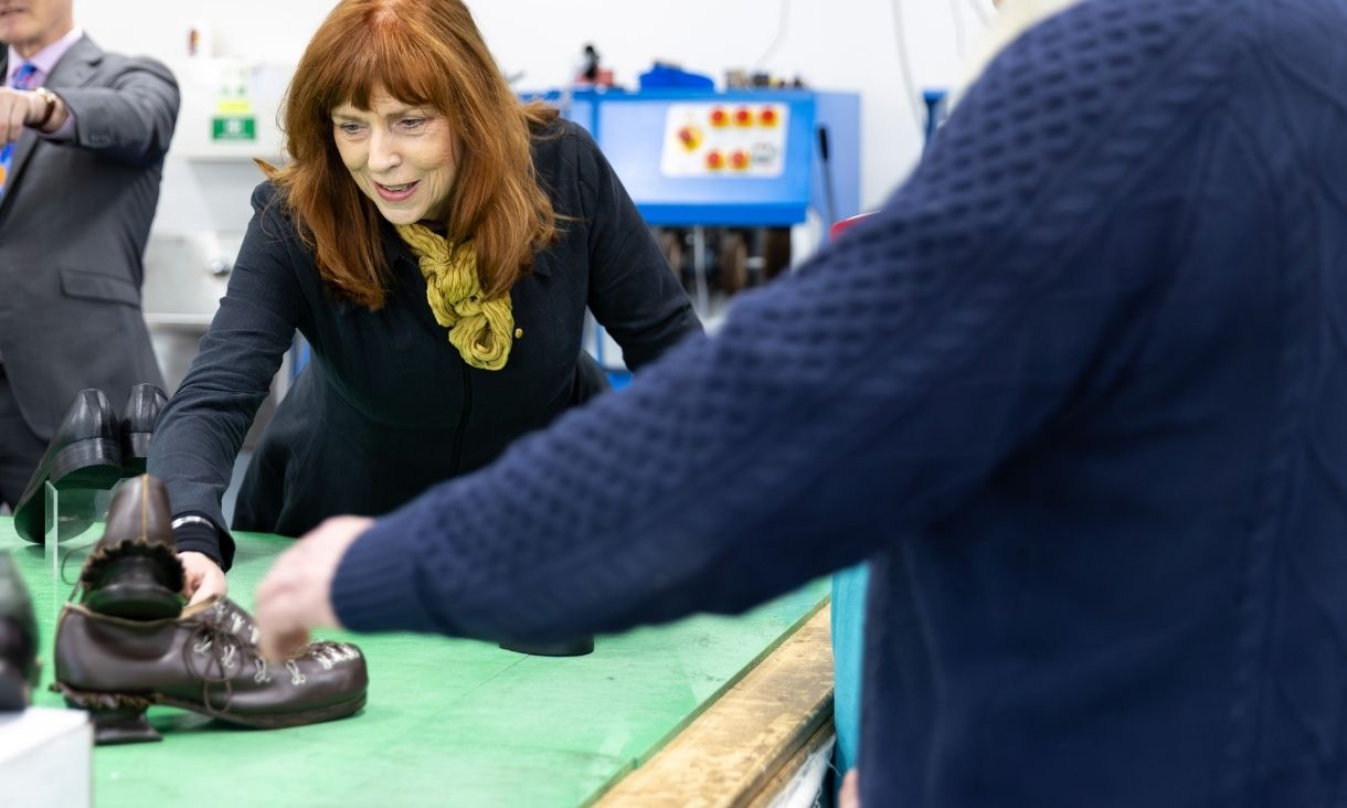 Her Excellency Professor the Honourable Margaret Gardner AC holds a shoe made by RMIT students. She is smiling.