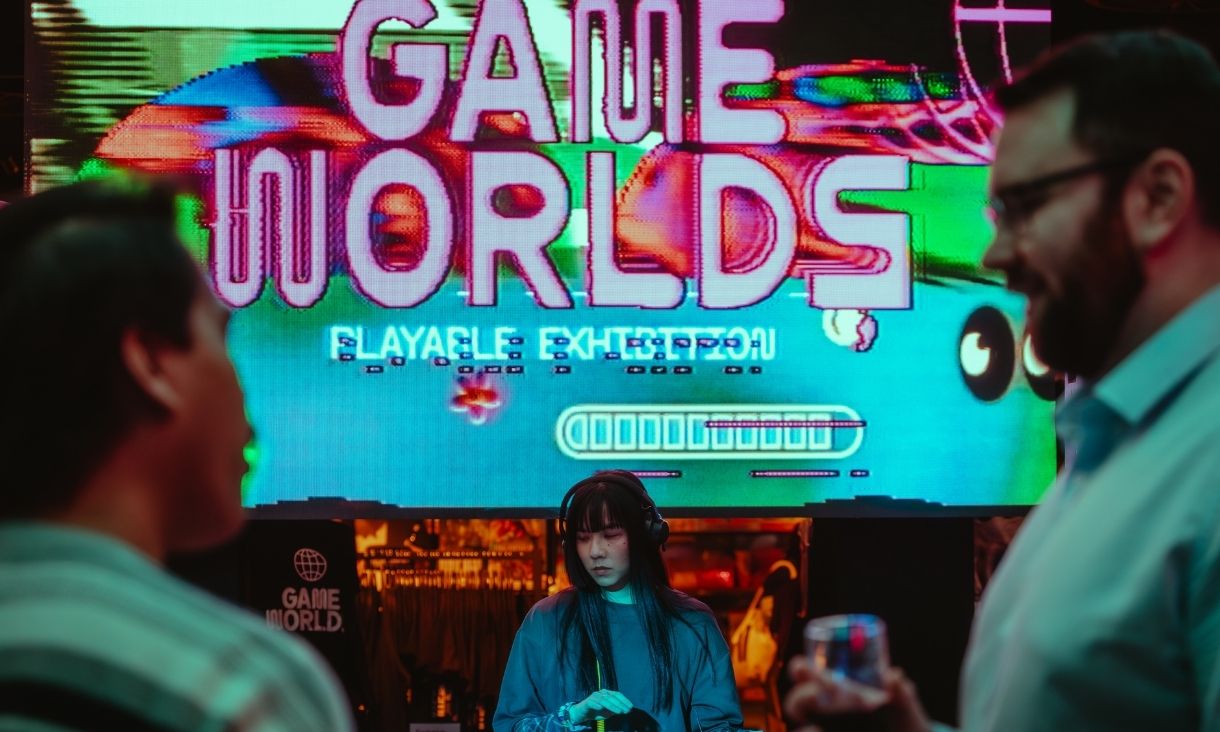 A DJ works in front of a screen which looks funky, saying 'Game Worlds'.