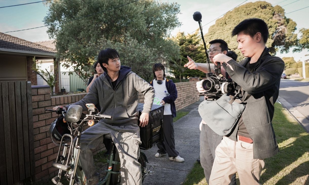 A camera crew films a man on a bike on a suburban Aussie street