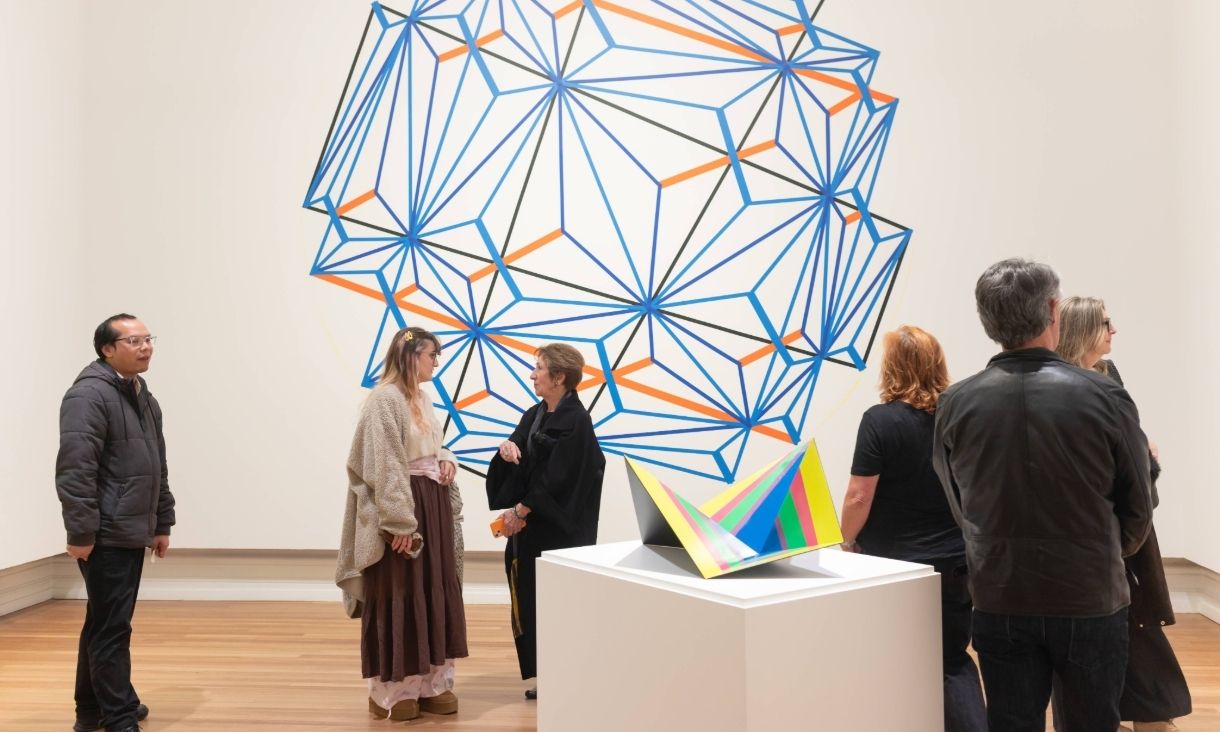  A large group of people stand in the exhibition, displaying colourful shapes 