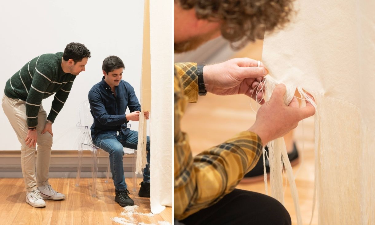 two people interact with the installation, white stands are tangled in their hands