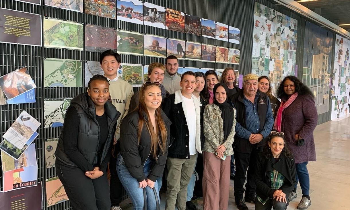 Group of students and people pose infront of a photo wall
