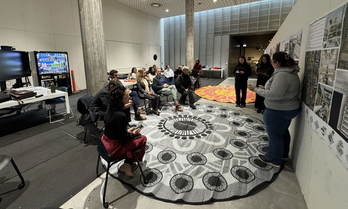 A group of people sit around together listening to presenters.