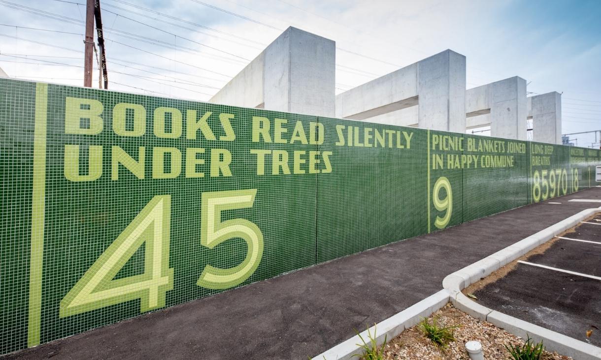 A large wall has tiled words reading - Books read silently under trees: 45