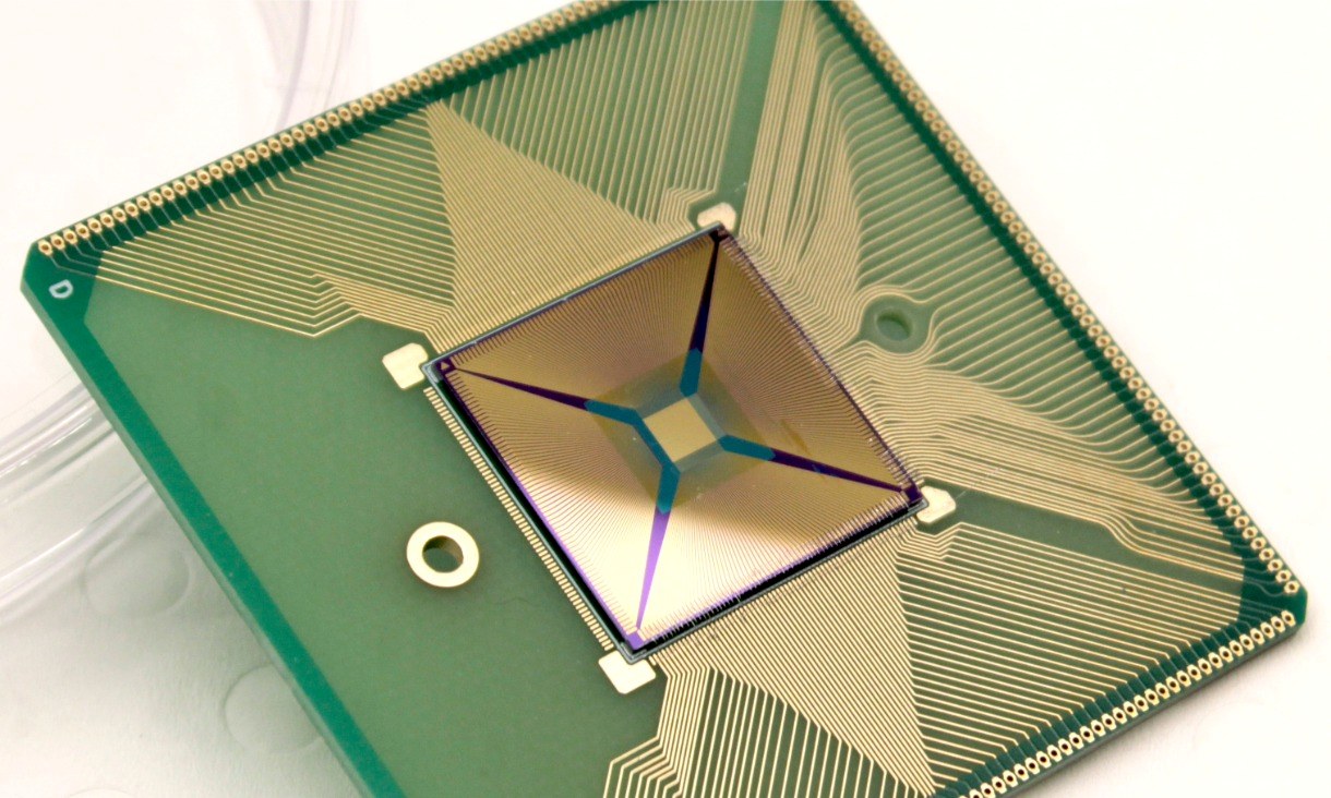 Magnified view of a square sensor enclosed within a dark protective mount on a semiconductor chip.
