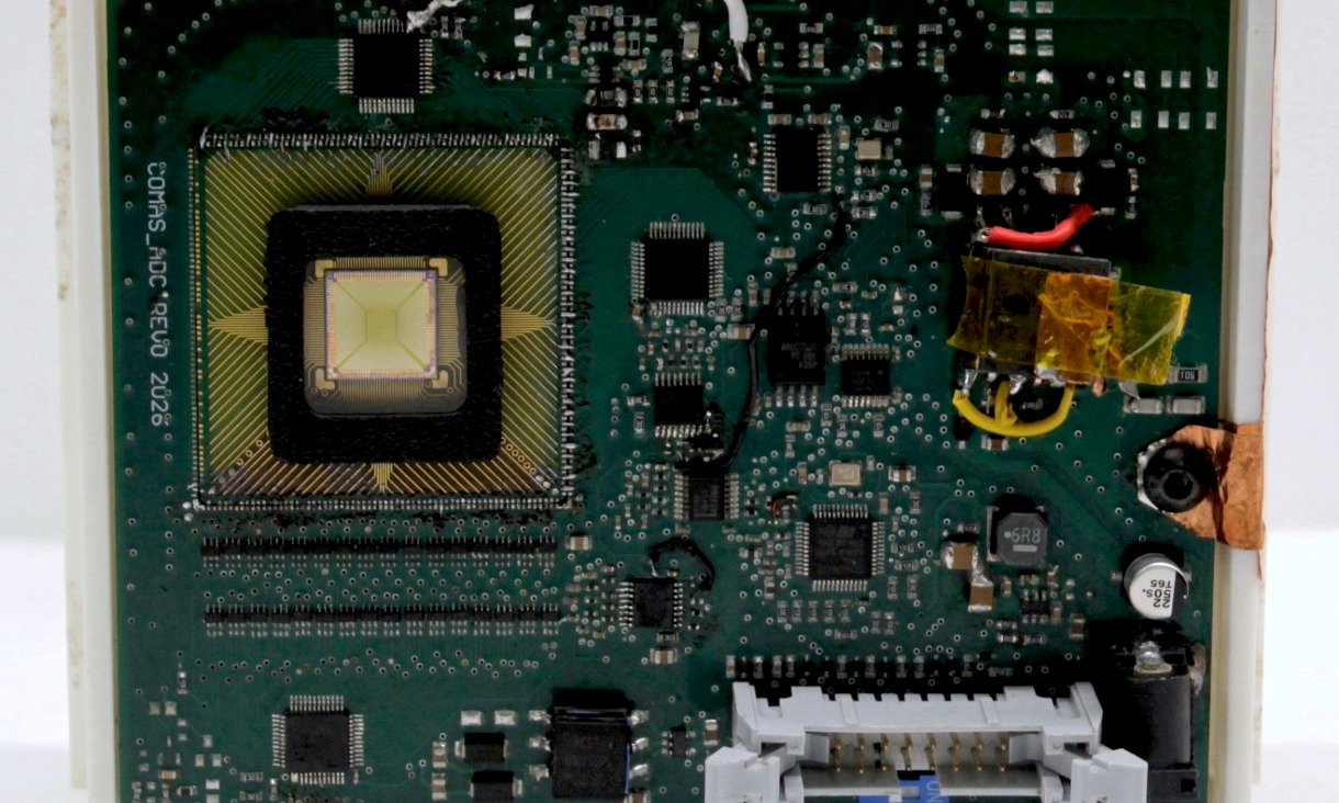 Electronic circuit board containing a square neuromorphic sensor mounted at the centre, with connectors and supporting electronic components surrounding it.