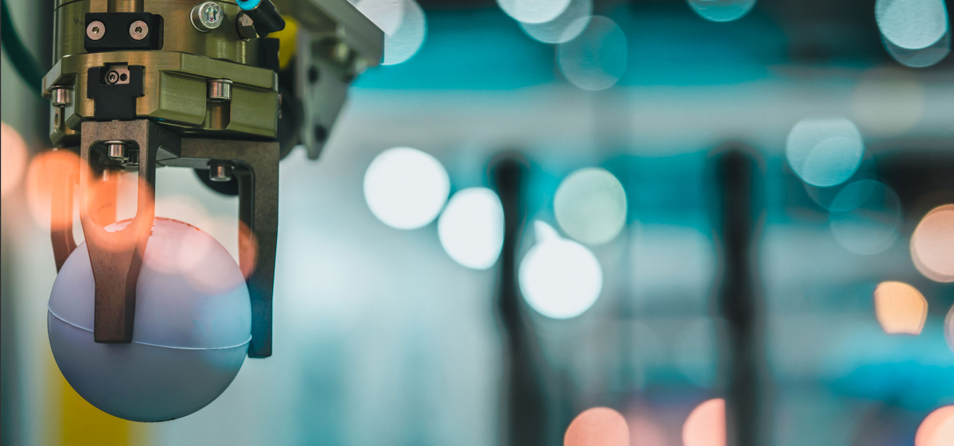 Closeup robot hand machine picking up white ball on bokeh blurred background. Use smart robot in manufacturing industry. Robotic tool in factory. Robot engineering concept 