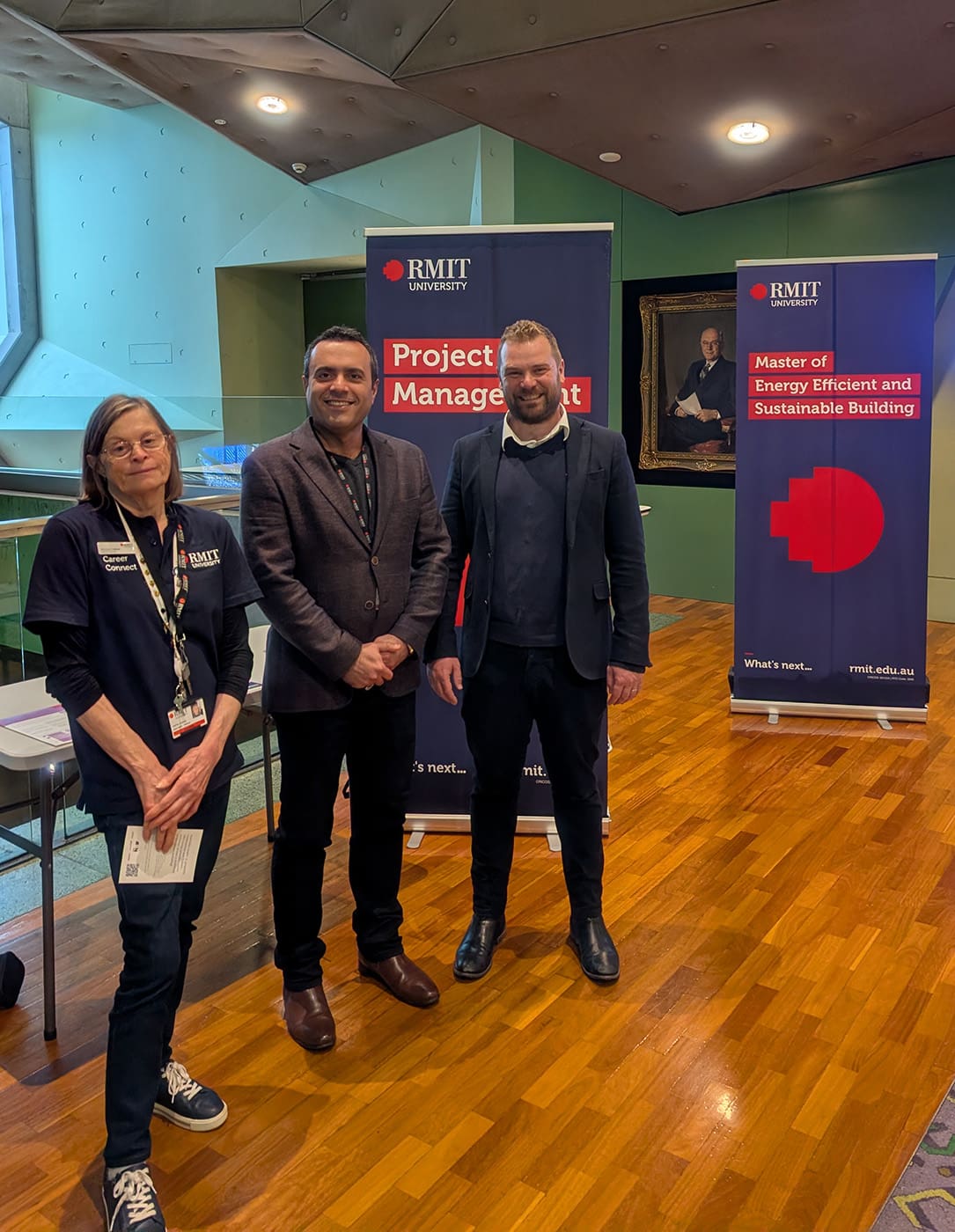 Three staff standing in front of banners at the PCPM careers fair.