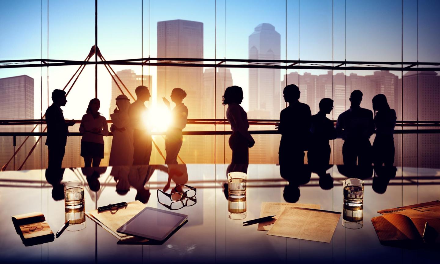 Silhouettes of workers in a high-rise corporate office, with city buildings in the background