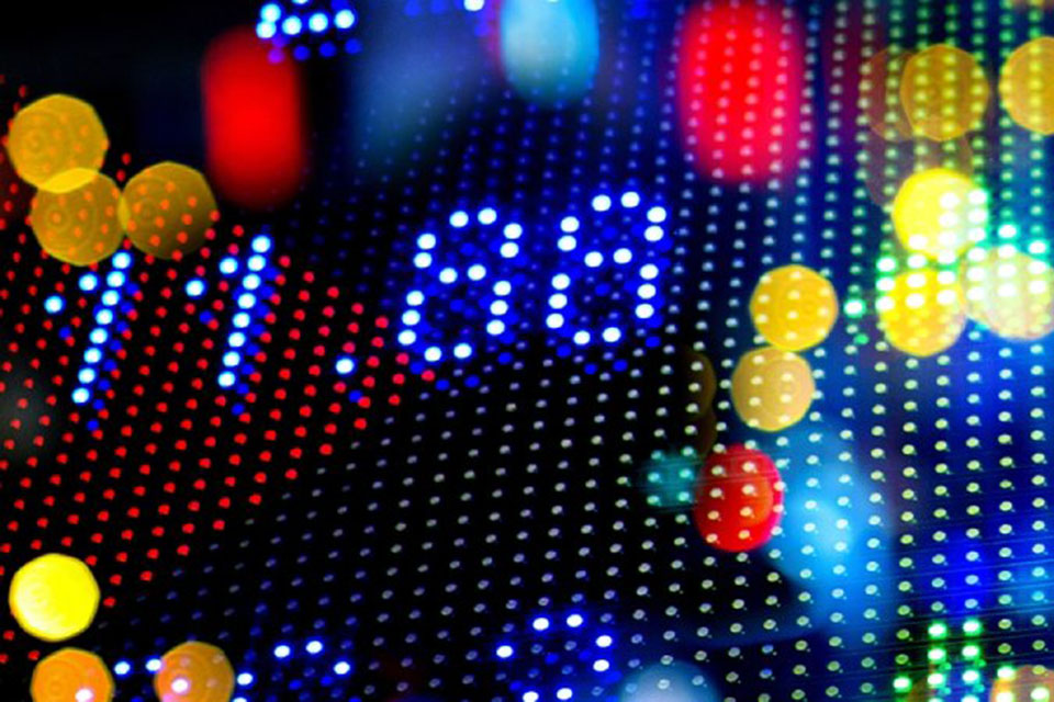 Close-up of a digital financial display showing numbers and colorful lights, representing stock market or financial data.