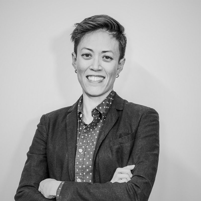 Greyscale photo of Serene Ho, arms folded, standing in front of white background.