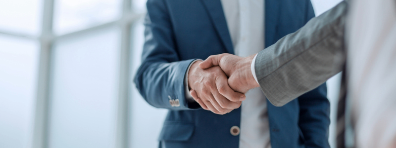 Stock photo of a close-up of a handshake between two people in formal attire.