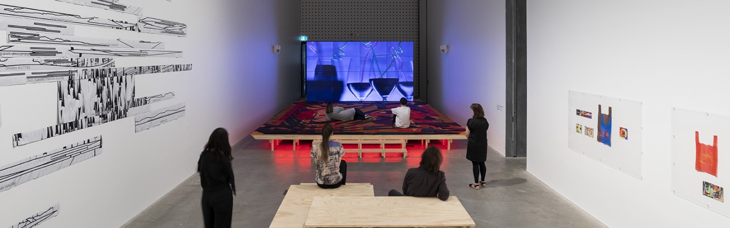 A photo of people watching a video installation in a gallery