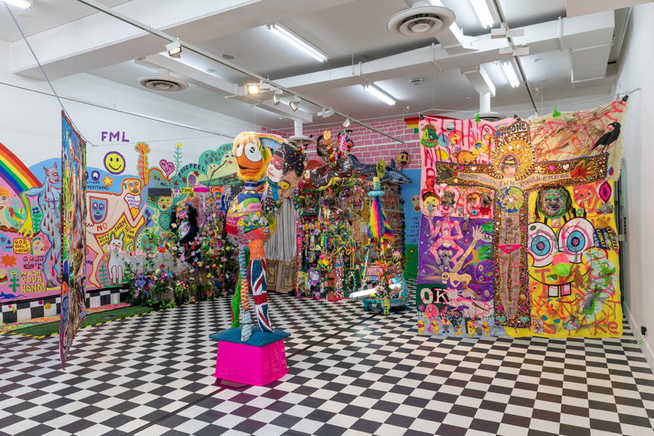 A vivid, neon coloured installation featuring tapestries, sculpture and murals