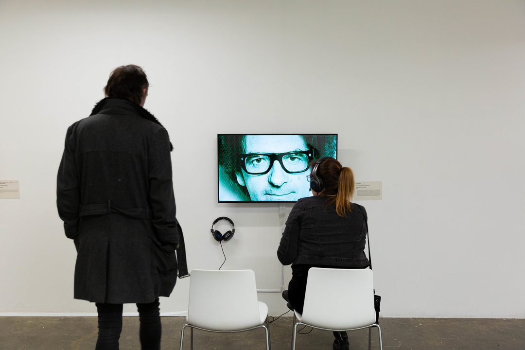 Back view of two people watching screen in gallery