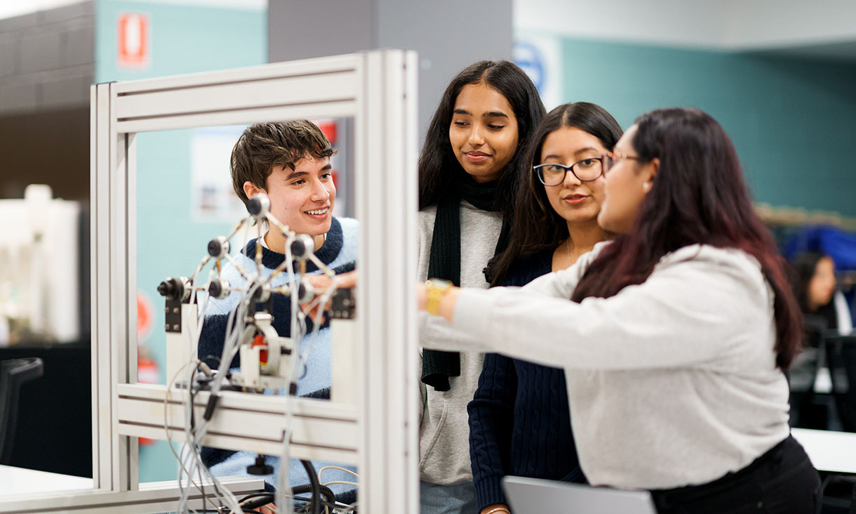 Group of engineering students working together on equipment in a lab.