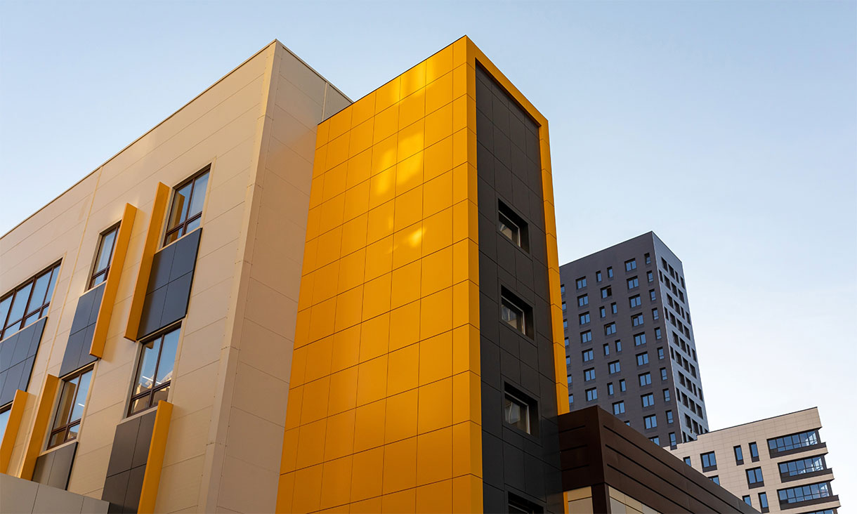 Modern building with yellow and grey facade panels against a clear sky.