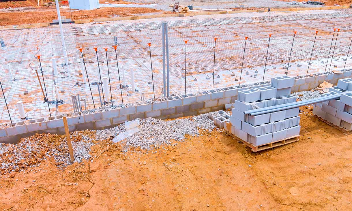 Concrete foundation under construction with pipes and reinforcement grids.