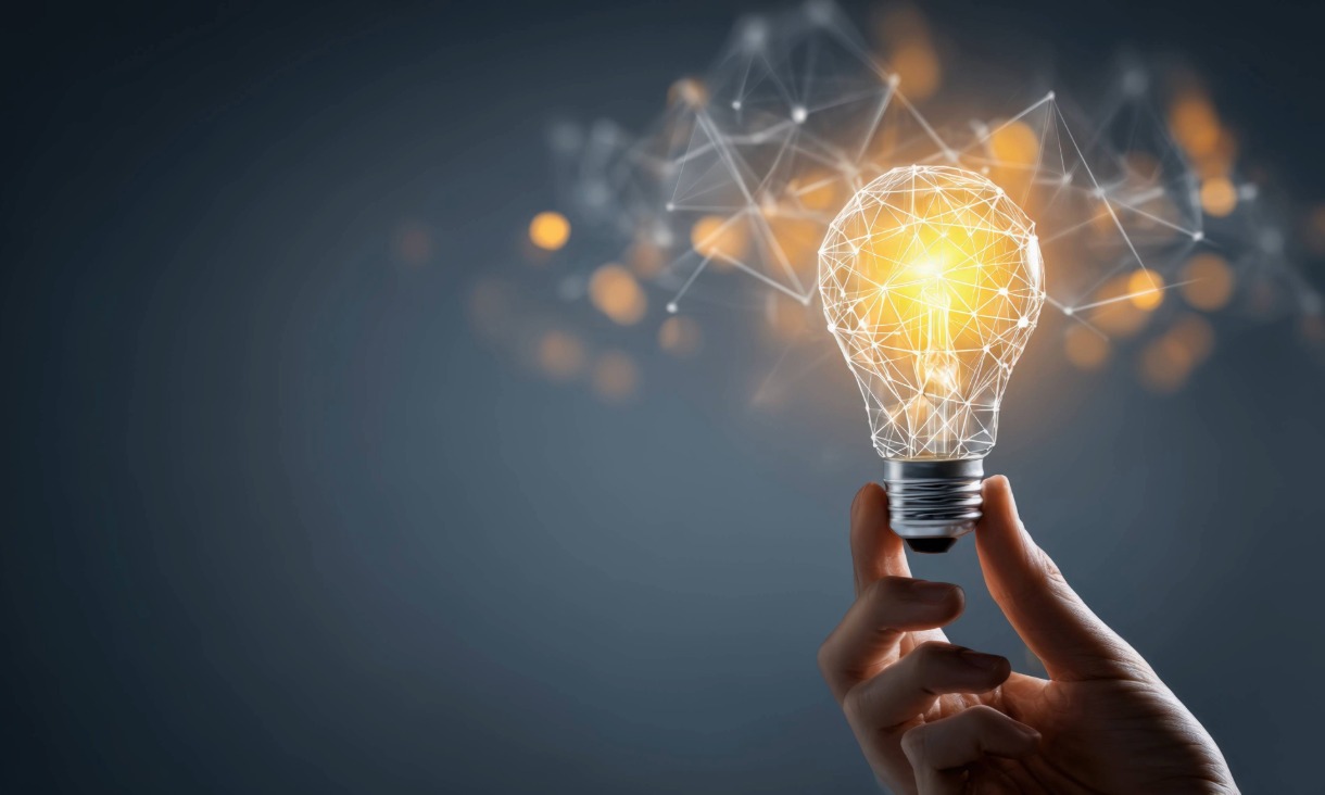 Hand holding a glowing, geometric light bulb against a dark background, symbolising innovation and creative ideas.
