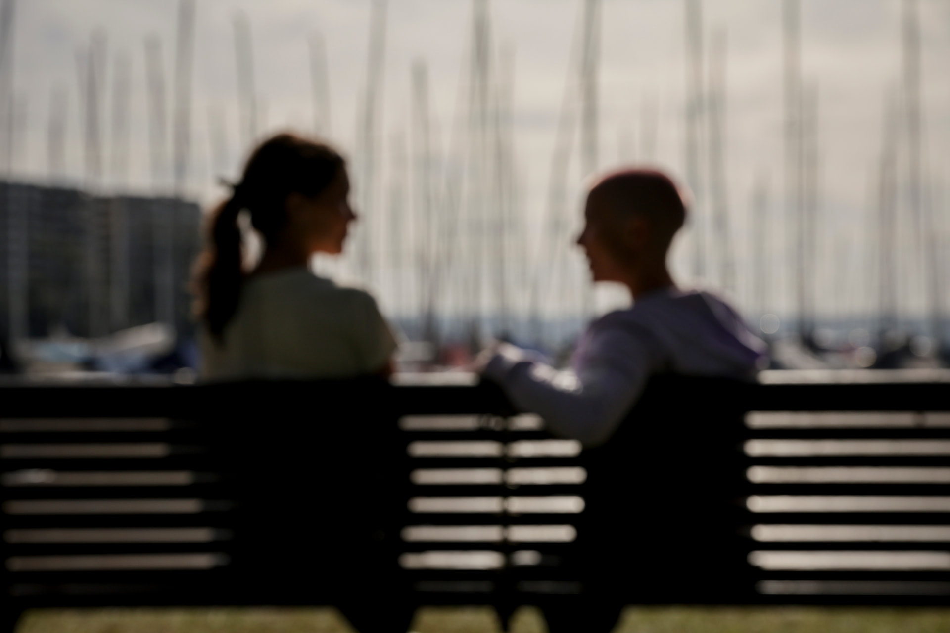 Blurred silhouettes of two people sitting on bench talking