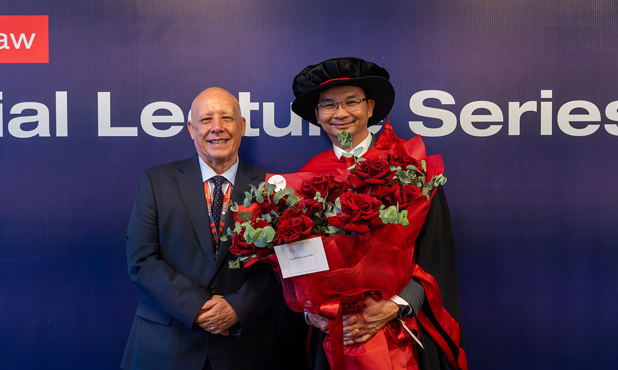 Trung holding celebratory flowers with Dean of TBS, Robert