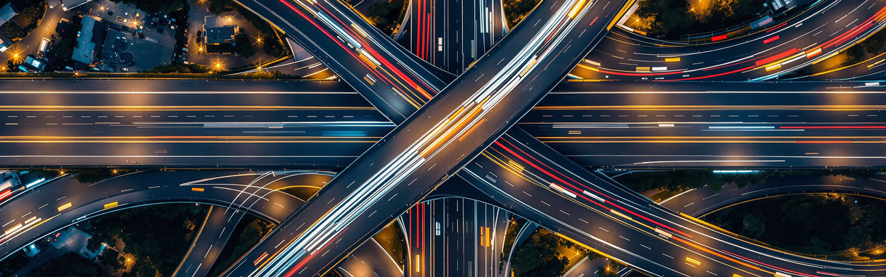 Complex highway interchange with colorful light trails, futuristic design style, night urban background, concept of modern transport infrastructure.