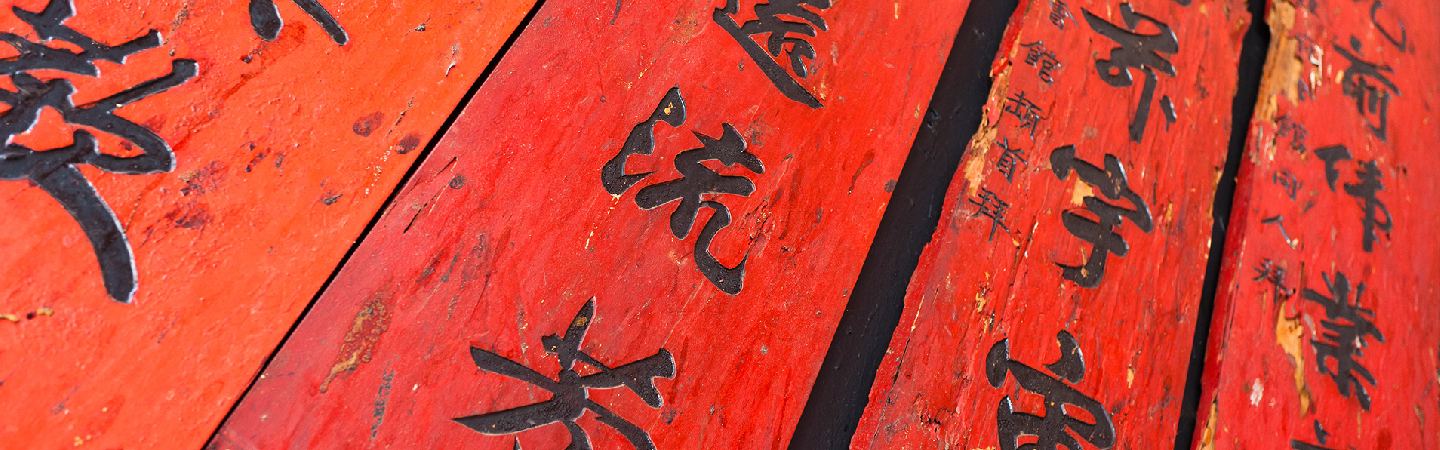 Close-up shot of Chinese characters carved onto red wooden planks