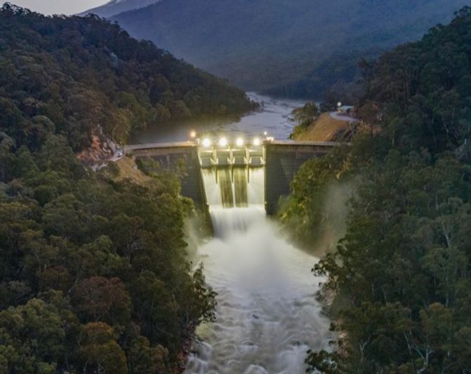Snowy Hydro 2.0 project with water cascading from dam with greenery either side