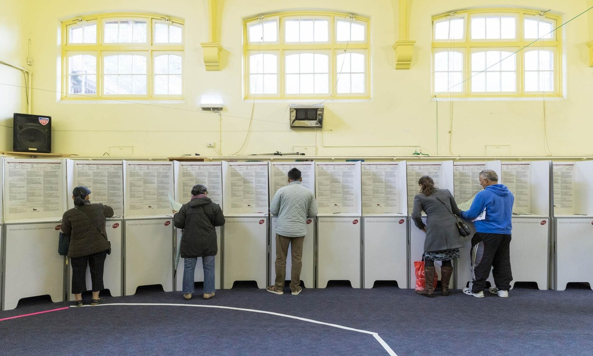 Five people voting at booths during  a state election