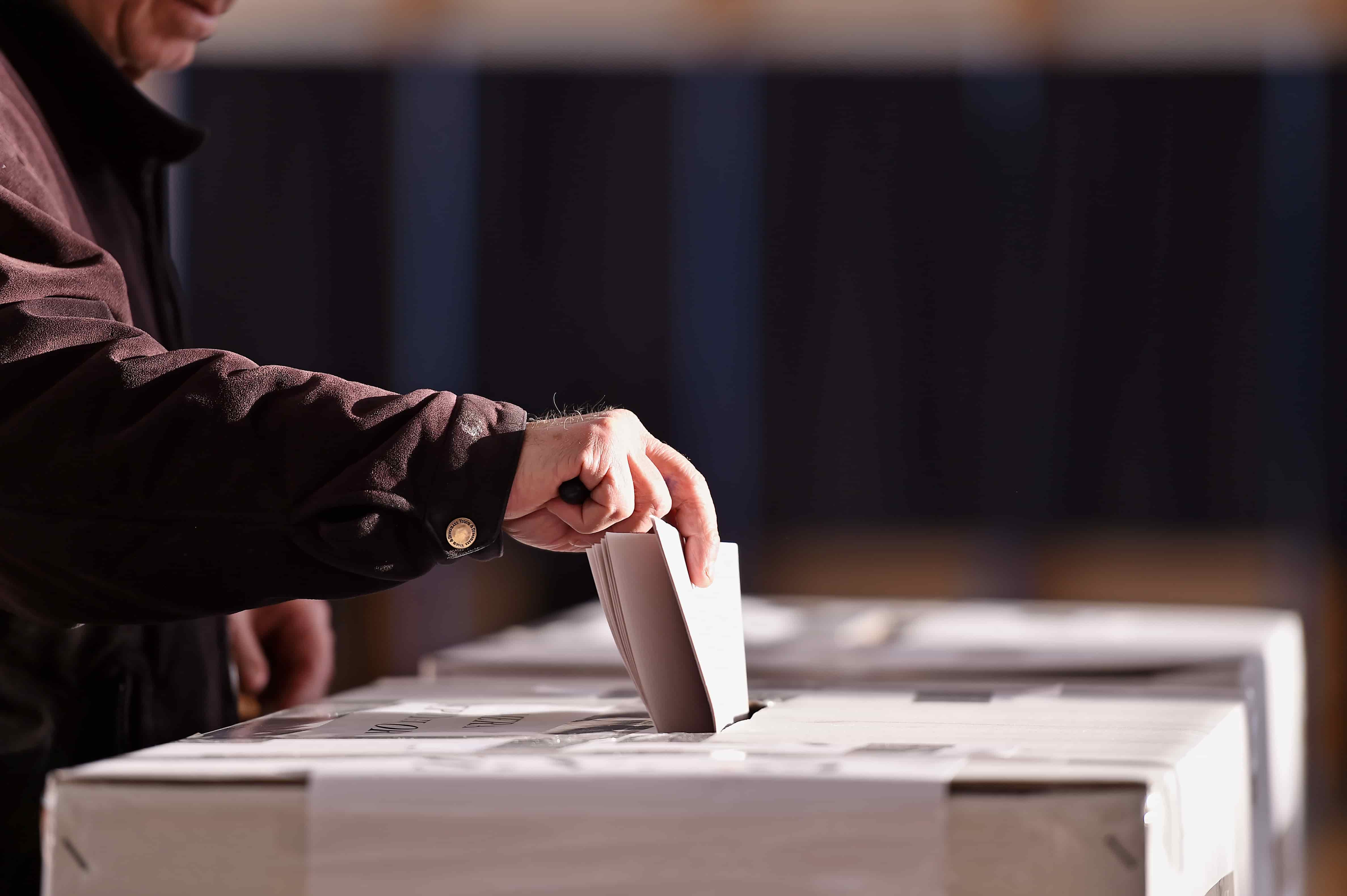 Hand casting a vote at ballot box