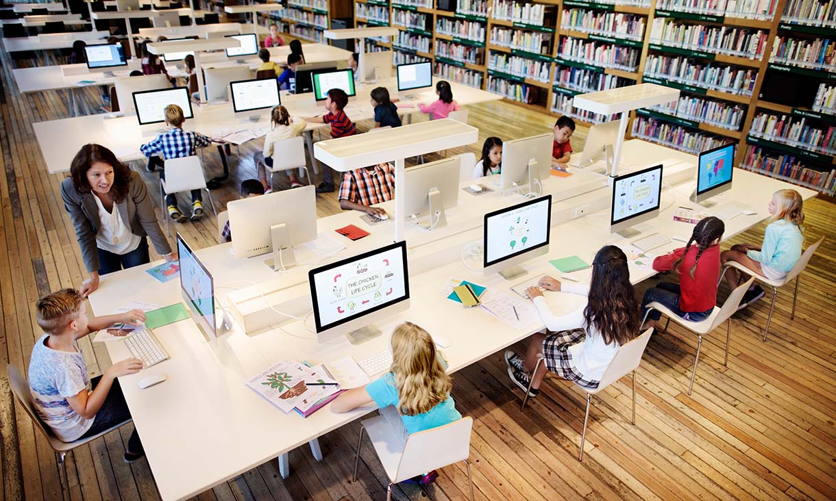 A library with a class of children working in front of computers