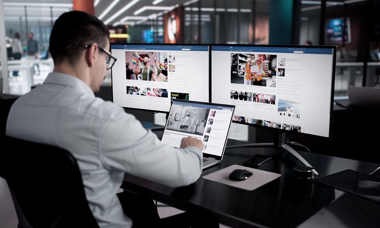 A man conducting an investigation at a computer with three screens