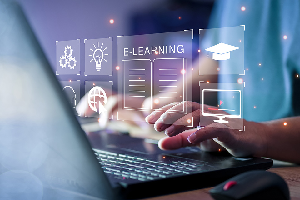 Computer icons and the word "e-learning" superimposed over a person typing on a laptop